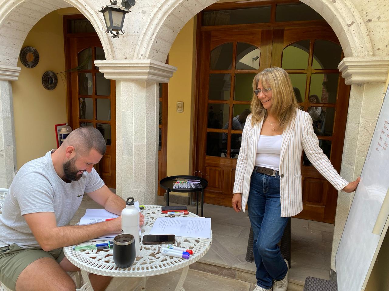 A student filling out some Spanish learning exercises with Maria on the right, who runs the Spanish school